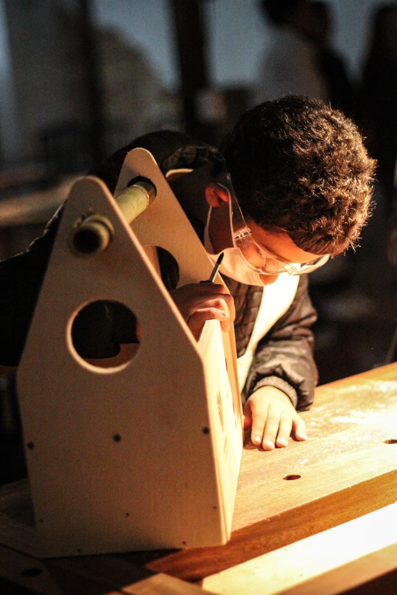 A child drawing beside a wooden object in the workshop